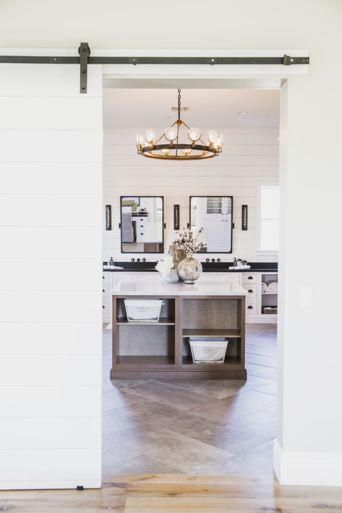 Bathroom seen through a sliding barn door with a chandelier over the vanity island