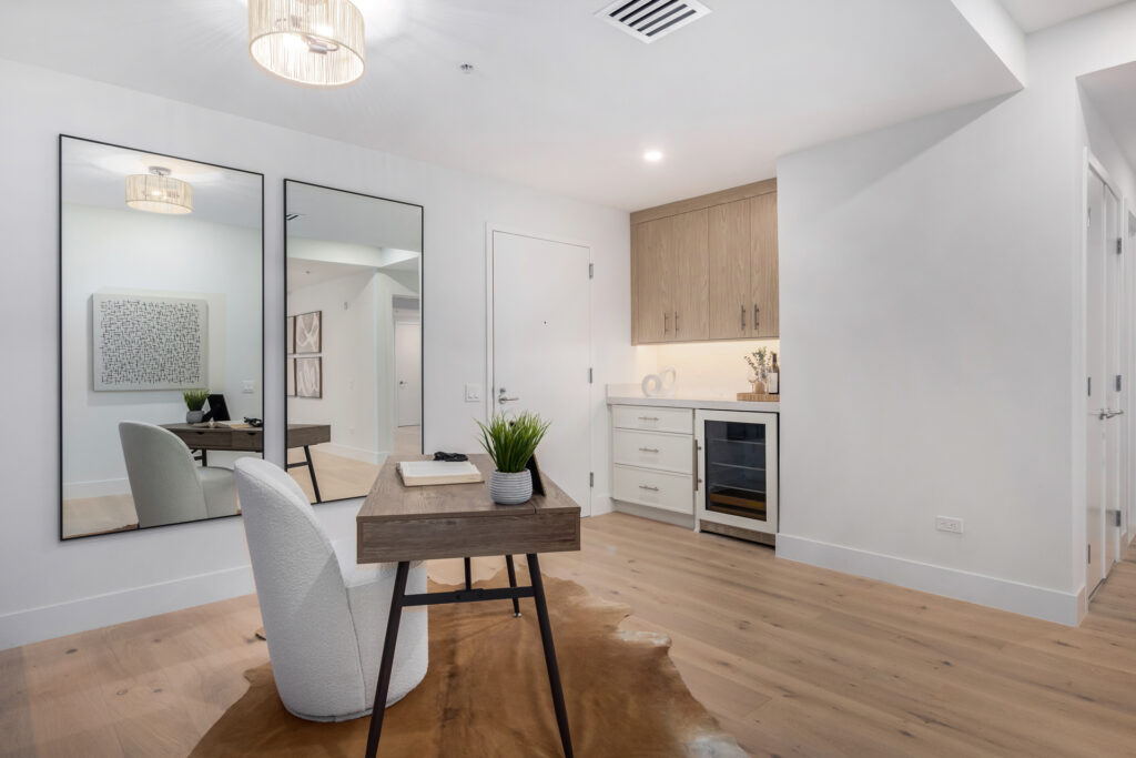 Office nook with a desk, boucle chair, tall mirrors and a wine refrigerator
