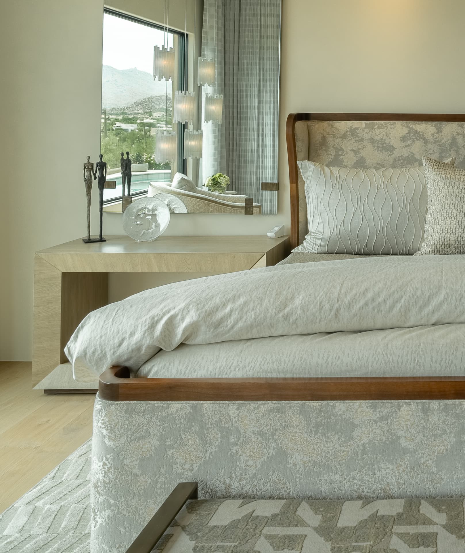 Bedroom with a low bed frame, nightstand and a window reflecting the desert outside