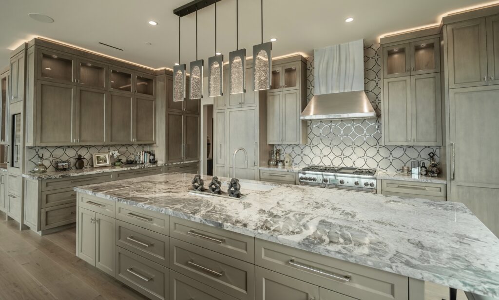 Kitchen with a marble-topped island, geometric tile backsplash and a stainless steel range
