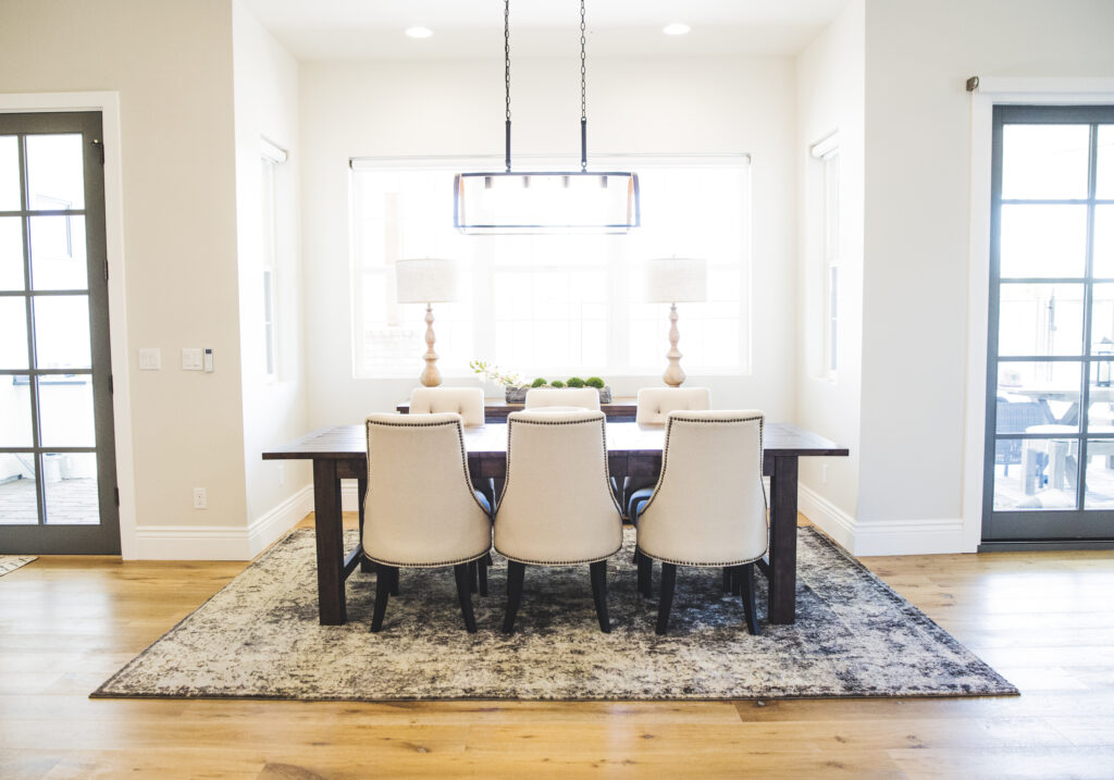 Dining room with a dark wood table, cream upholstered chairs and a linear chandelier