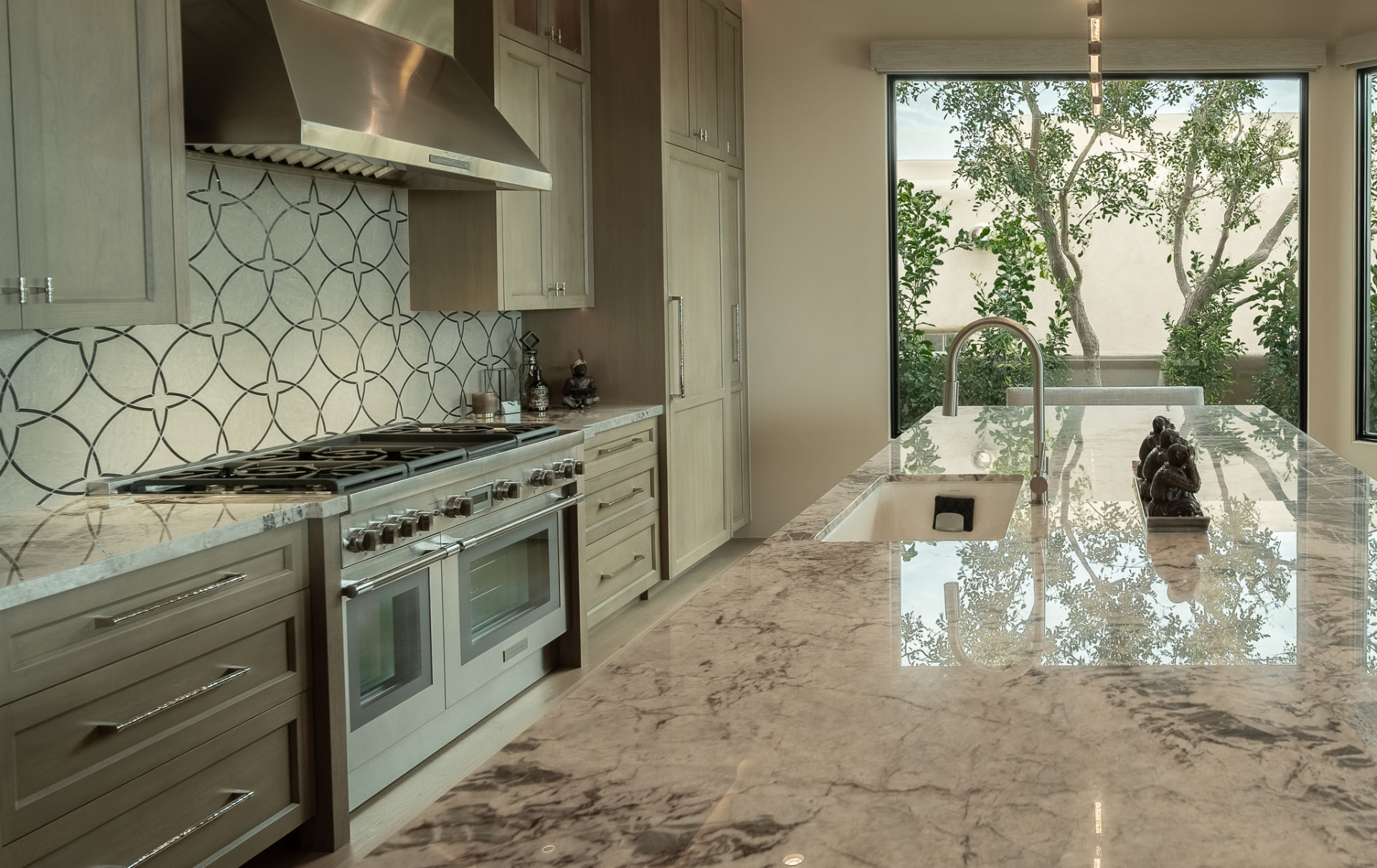 Kitchen looking along the island countertop to the sink, gas range and a garden window