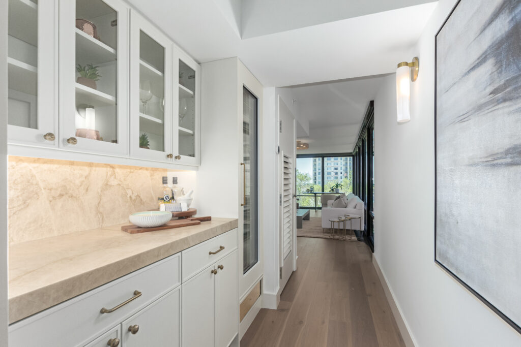 Hallway wet bar with glass-front cabinets, an integrated wine refrigerator and abstract wall art