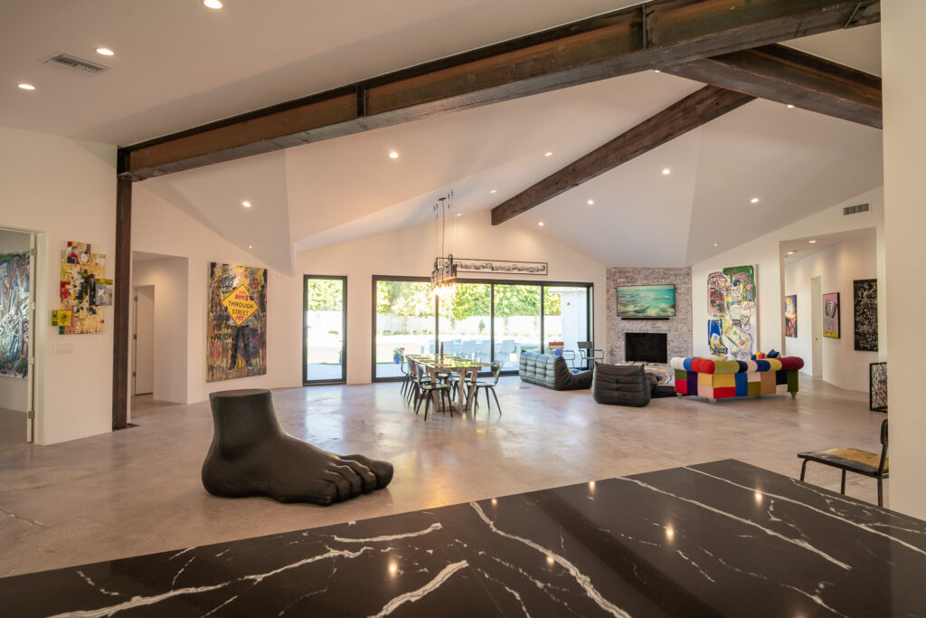 Open living and dining room with exposed beams and contemporary artwork