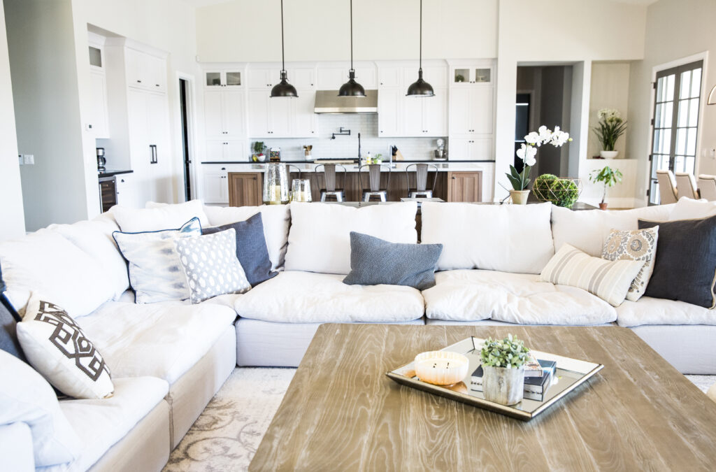 Great room with a large sectional sofa facing the open kitchen with black pendant lights