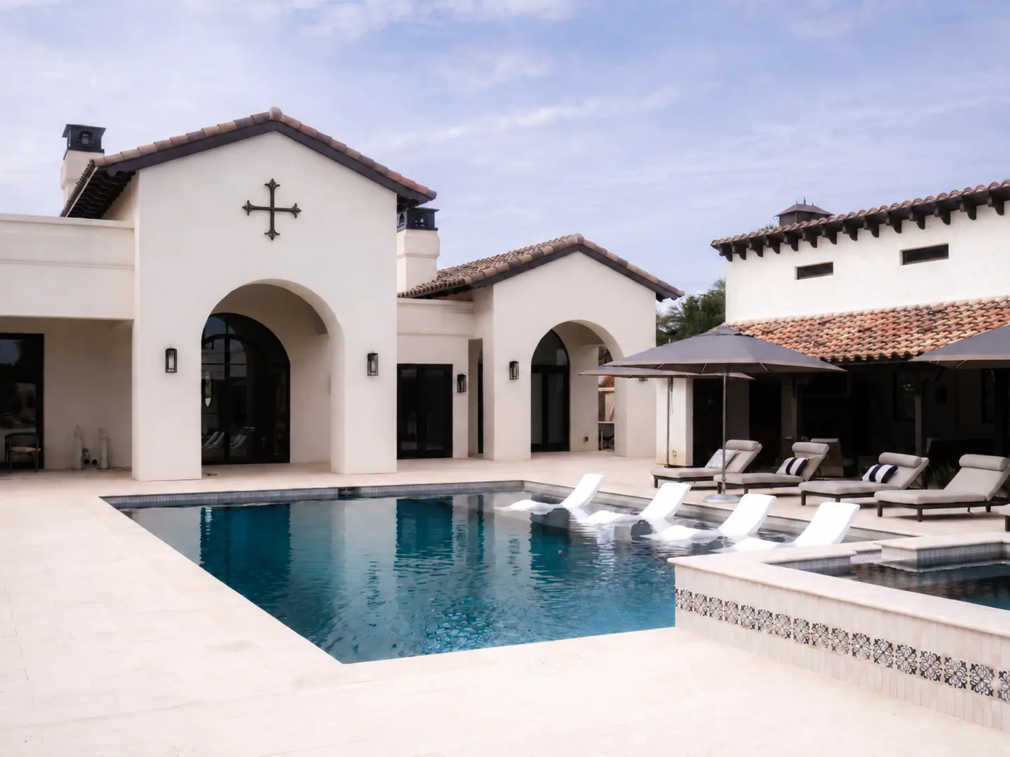 Spanish-style luxury residence with arched entry opening onto a pool