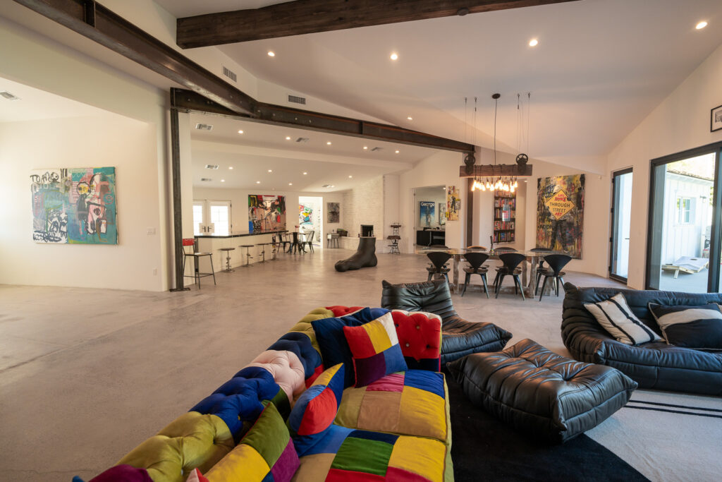 Living and dining room with colorful seating beneath exposed beams