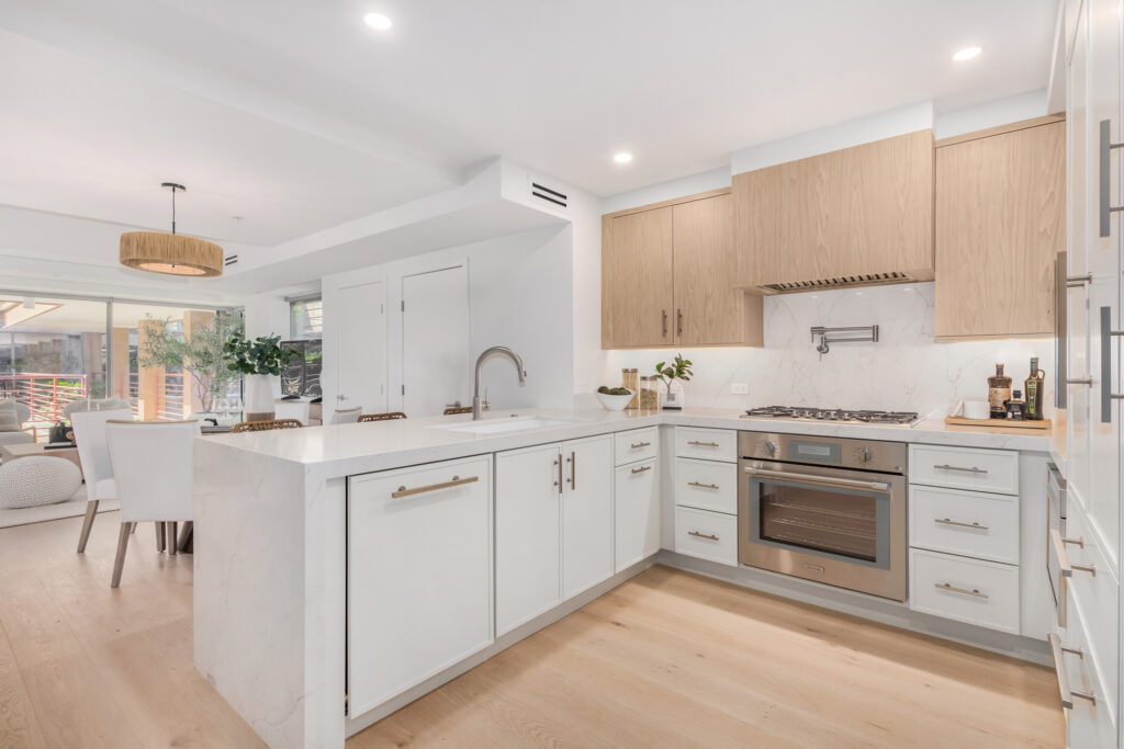 Kitchen with a waterfall marble peninsula, light oak cabinetry and stainless steel oven