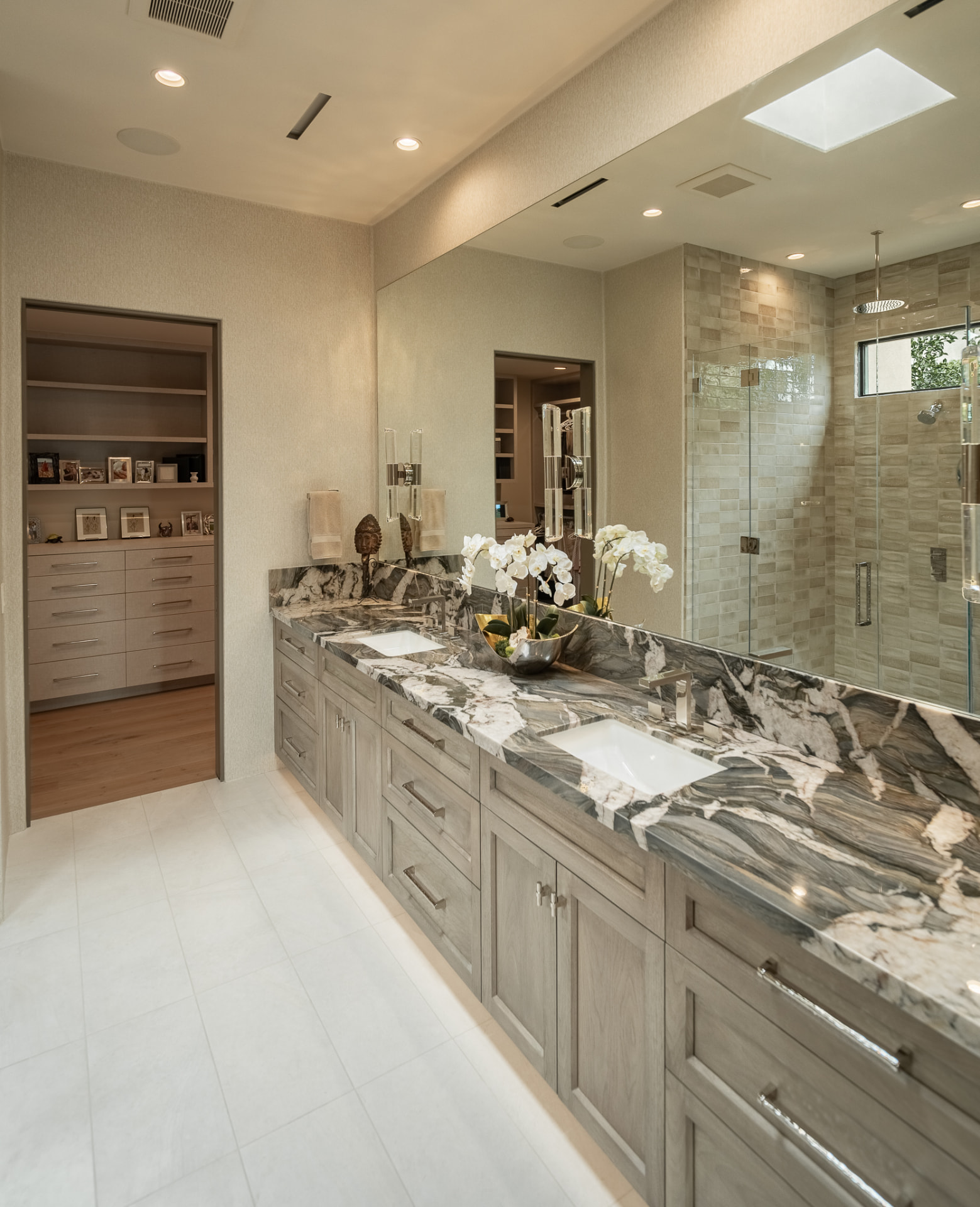 Bathroom with a double-sink marble vanity and a large mirror beside the walk-in closet
