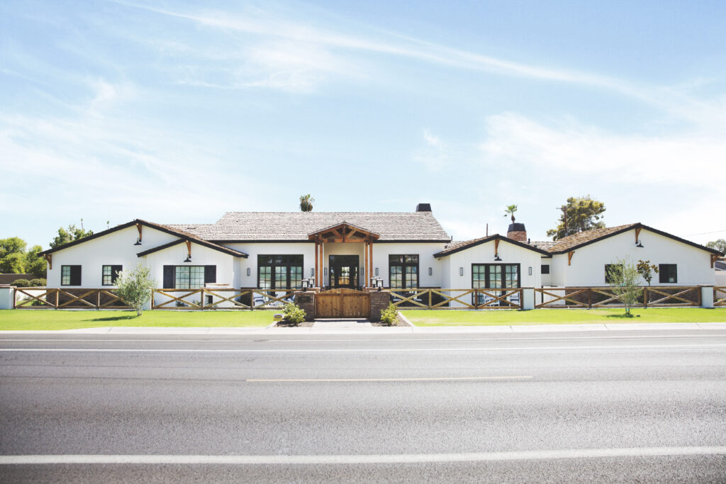 Arcadia Modern Ranch exterior with white siding, cedar brackets and a cross-buck fence along the street