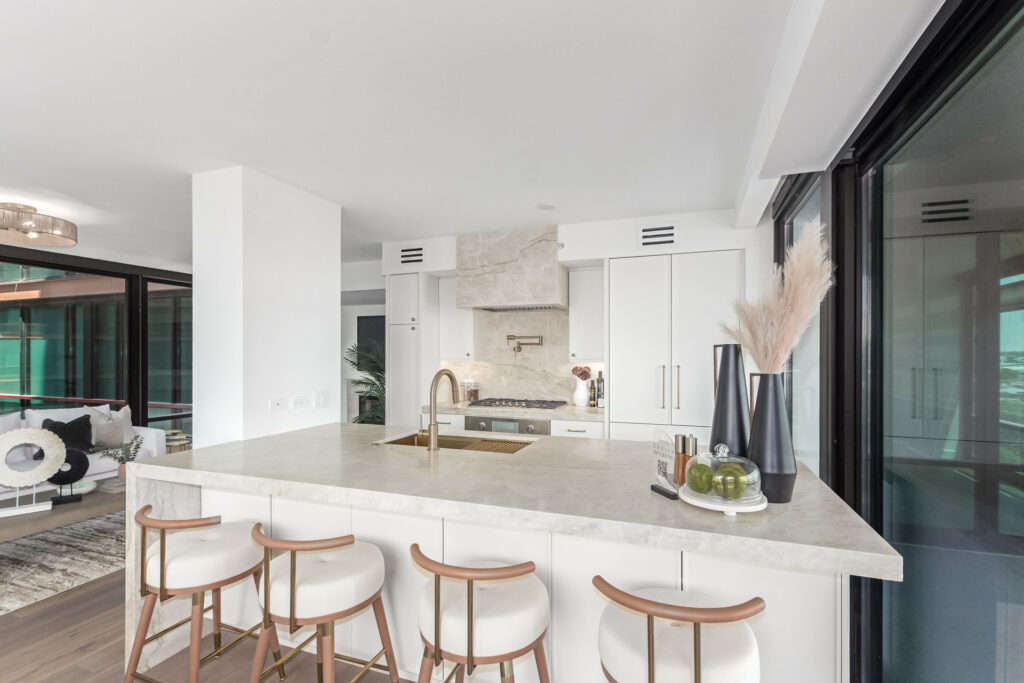 Kitchen with a marble waterfall island, stone range hood and white cabinetry