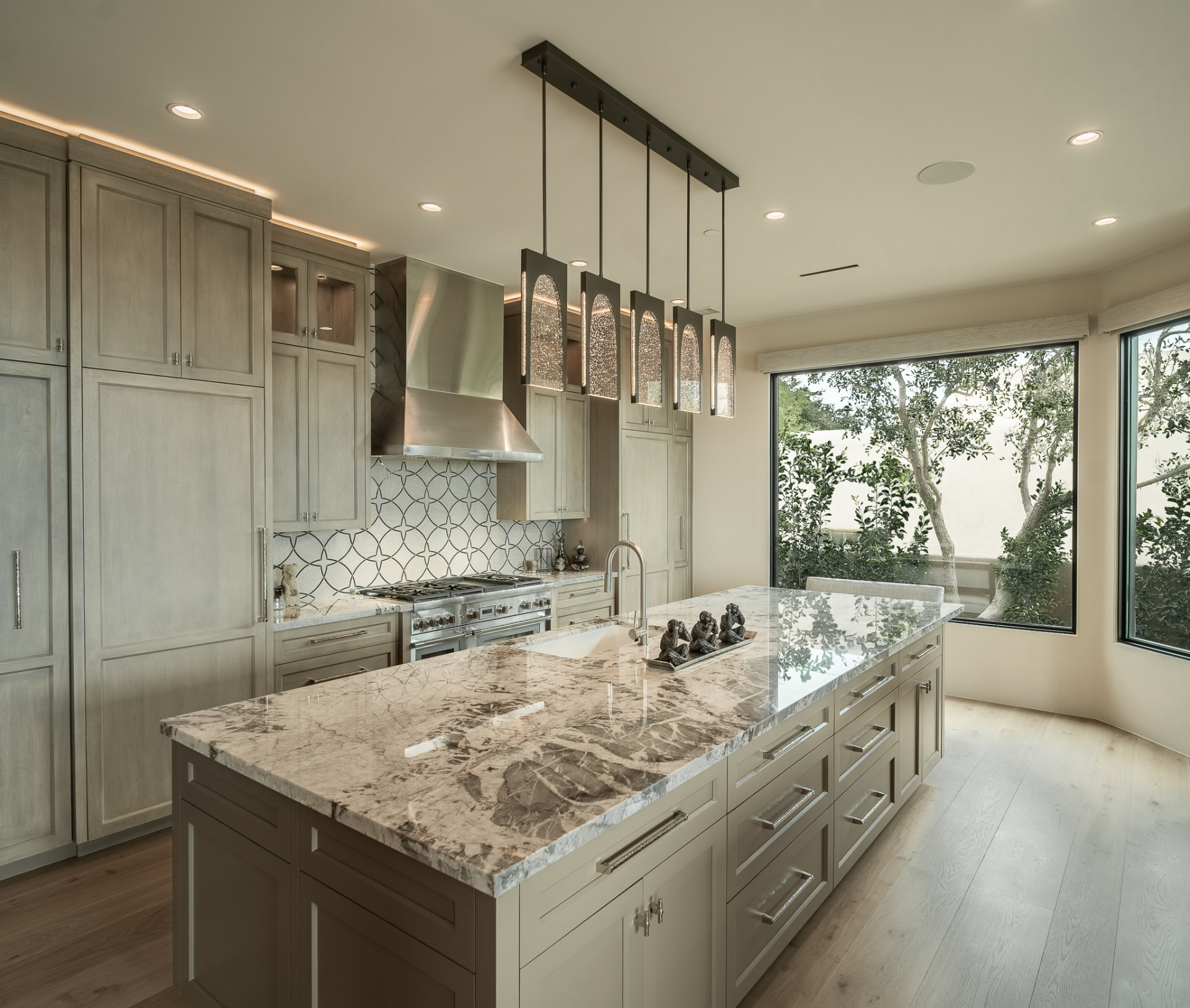 Kitchen with a marble island, textured-glass pendant light, professional gas range and a geometric tile backsplash