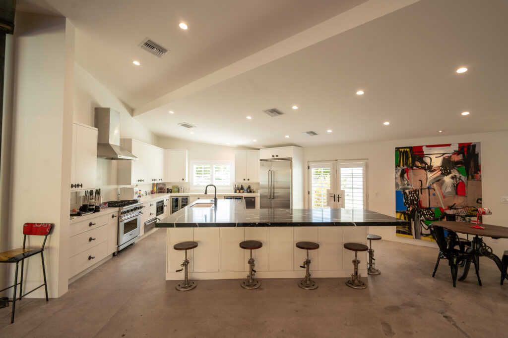 White kitchen with a large dark stone island and stainless steel appliances